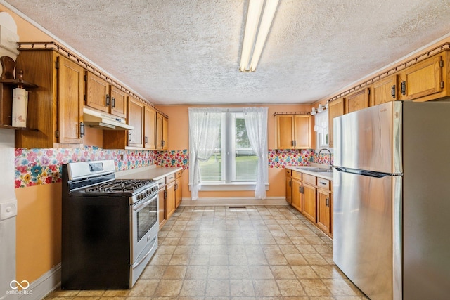 206 E Franklin St, Roachdale, IN 46172 - kitchen featuring appliances with stainless steel finishes, under cabinet range hood, light countertops, a textured ceiling, and brown cabinetry