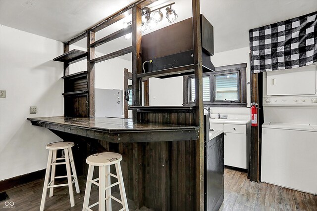 115 Simpson St, Crawfordsville, IN 47933 - kitchen with estacked washer and dryer, light wood-style floors, a kitchen bar, white cabinets, and open shelves