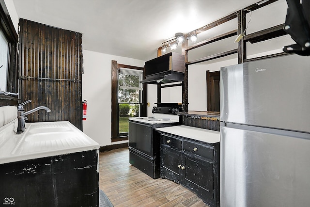115 Simpson St, Crawfordsville, IN 47933 - kitchen featuring freestanding refrigerator, black range with electric stovetop, light wood-style floors, ventilation hood, and dark cabinets