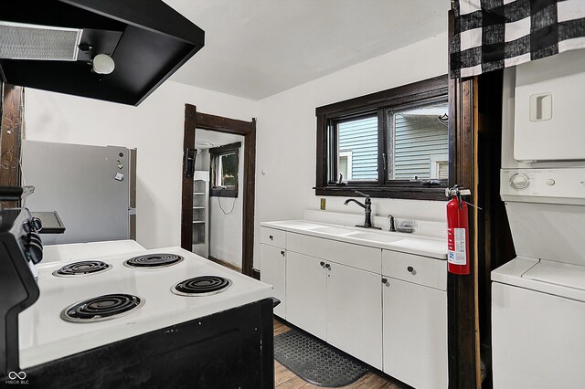 115 Simpson St, Crawfordsville, IN 47933 - kitchen featuring stacked washer and clothes dryer, range with electric cooktop, exhaust hood, freestanding refrigerator, and light countertops