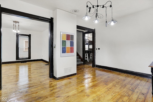 115 Simpson St, Crawfordsville, IN 47933 - empty room with stairway, hardwood / wood-style floors, and a chandelier