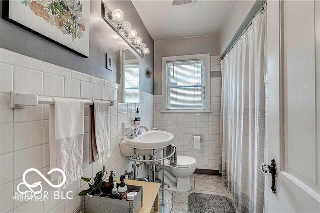 5363 Primrose Ave, Indianapolis, IN 46220 - full bath featuring tile walls, tile patterned floors, curtained shower, and wainscoting