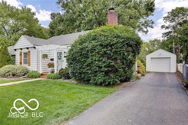 5363 Primrose Ave, Indianapolis, IN 46220 - view of front of property with a detached garage, an outbuilding, a chimney, a front lawn, and asphalt driveway