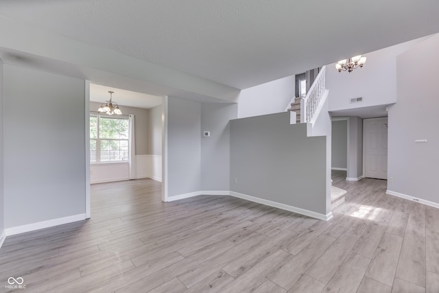 7914 Willow Wind Cir, Indianapolis, IN 46239 - unfurnished living room with a chandelier, light wood-style floors, and stairway