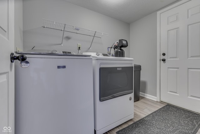 7914 Willow Wind Cir, Indianapolis, IN 46239 - laundry room featuring separate washer and dryer, light wood-type flooring, and a textured ceiling