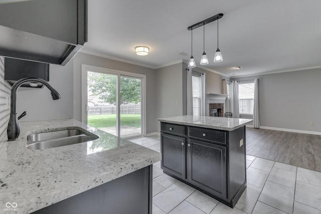 7914 Willow Wind Cir, Indianapolis, IN 46239 - kitchen featuring dark cabinetry, ornamental molding, plenty of natural light, a fireplace, and hanging light fixtures
