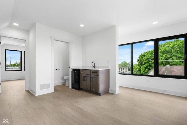 1100 English Ave, Indianapolis, IN 46203 - kitchen with wine cooler, light countertops, recessed lighting, light wood-style flooring, and dark brown cabinetry