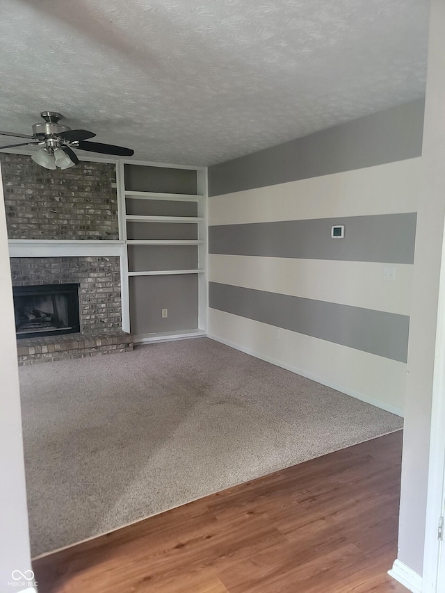 922 Eagle Brook Dr, Shelbyville, IN 46176 - unfurnished living room with a ceiling fan, a textured ceiling, wood finished floors, a fireplace, and carpet