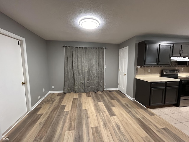 3525 Valley Lake Dr, Indianapolis, IN 46227 - kitchen with electric range, light countertops, a textured ceiling, backsplash, and under cabinet range hood
