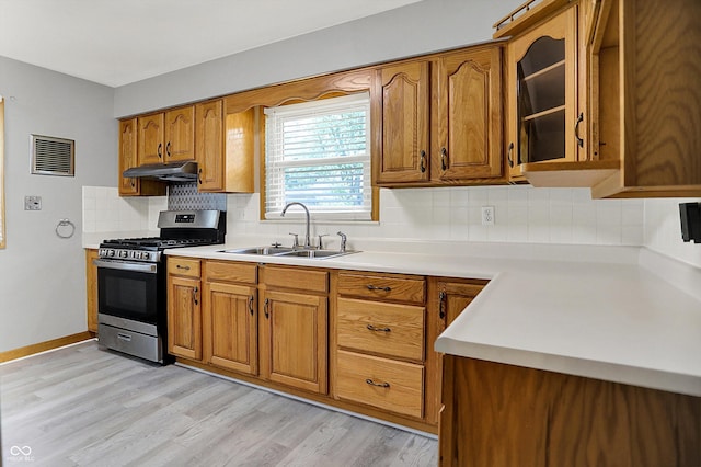 3322 N Riley Ave N, Indianapolis, IN 46218 - kitchen featuring stainless steel range with gas cooktop, under cabinet range hood, brown cabinets, and light countertops