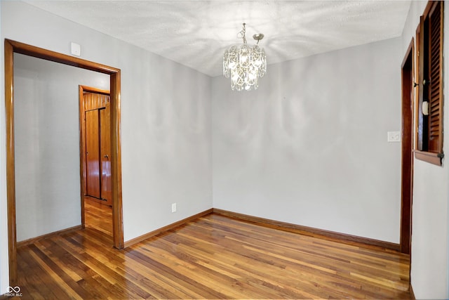 3322 N Riley Ave N, Indianapolis, IN 46218 - empty room with hardwood / wood-style flooring, a chandelier, and a textured ceiling