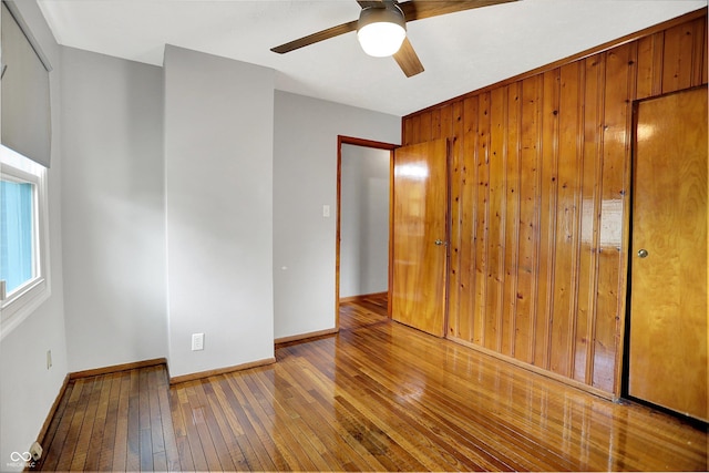 3322 N Riley Ave N, Indianapolis, IN 46218 - unfurnished bedroom featuring hardwood / wood-style flooring, wooden walls, a closet, and ceiling fan