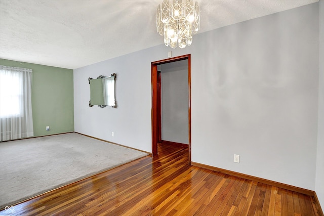 3322 N Riley Ave N, Indianapolis, IN 46218 - unfurnished room featuring hardwood / wood-style flooring, a chandelier, and a textured ceiling