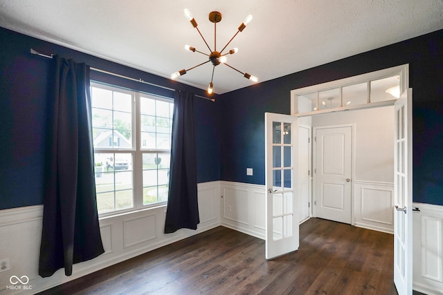 6670 Shooting Star Dr, Whitestown, IN 46075 - spare room featuring a chandelier, plenty of natural light, wainscoting, dark wood finished floors, and french doors