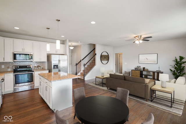 6670 Shooting Star Dr, Whitestown, IN 46075 - kitchen featuring stainless steel appliances, a center island, decorative backsplash, open floor plan, and light stone counters