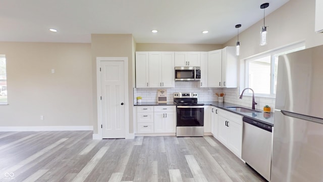 1809 S H St, Elwood, IN 46036 - kitchen featuring appliances with stainless steel finishes, dark countertops, tasteful backsplash, light wood-type flooring, and white cabinetry