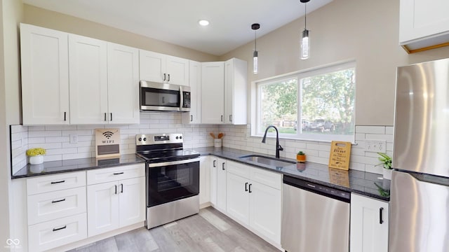 1809 S H St, Elwood, IN 46036 - kitchen with stainless steel appliances, dark stone countertops, white cabinetry, light wood finished floors, and pendant lighting