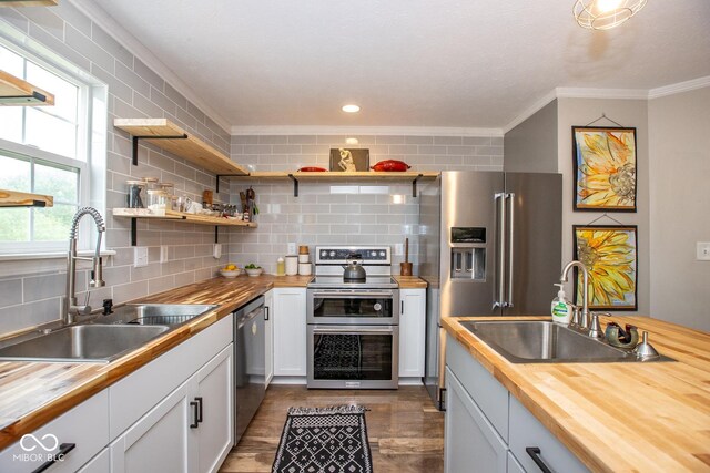 6532 Amherst Way, Zionsville, IN 46077 - kitchen featuring butcher block counters, stainless steel appliances, backsplash, ornamental molding, and white cabinetry
