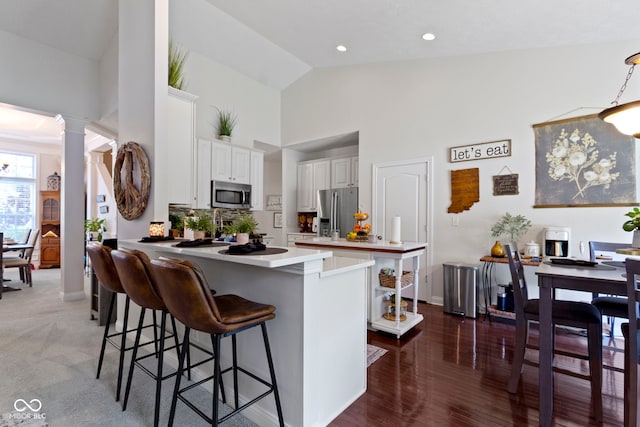 15098 Newburyport Dr, Fortville, IN 46040 - kitchen with stainless steel appliances, a peninsula, ornate columns, a kitchen bar, and high vaulted ceiling