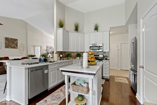 15098 Newburyport Dr, Fortville, IN 46040 - kitchen featuring stainless steel appliances, light countertops, a peninsula, dark wood finished floors, and tasteful backsplash
