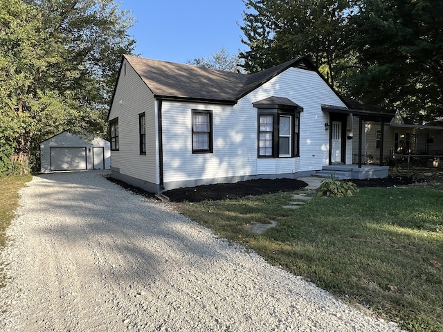 937 N Routiers Ave, Indianapolis, IN 46219 - view of front of house with an outdoor structure, a shingled roof, a detached garage, a front yard, and gravel driveway