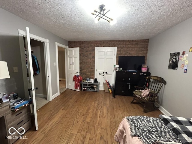 8407 Campbell Ct, Mooresville, IN 46158 - bedroom featuring wood finished floors, brick wall, and a textured ceiling