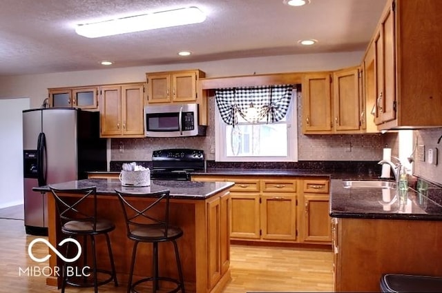 8905 Maze Rd, Indianapolis, IN 46259 - kitchen featuring appliances with stainless steel finishes, a kitchen island, light wood-type flooring, a breakfast bar area, and backsplash