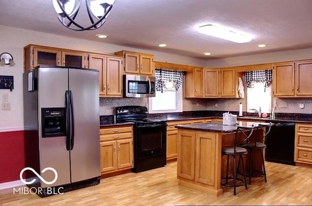 8905 Maze Rd, Indianapolis, IN 46259 - kitchen featuring black appliances, light wood-style flooring, tasteful backsplash, a center island, and a breakfast bar area