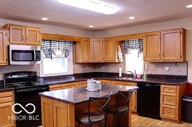 8905 Maze Rd, Indianapolis, IN 46259 - kitchen featuring black appliances, a center island, decorative backsplash, light wood-type flooring, and recessed lighting