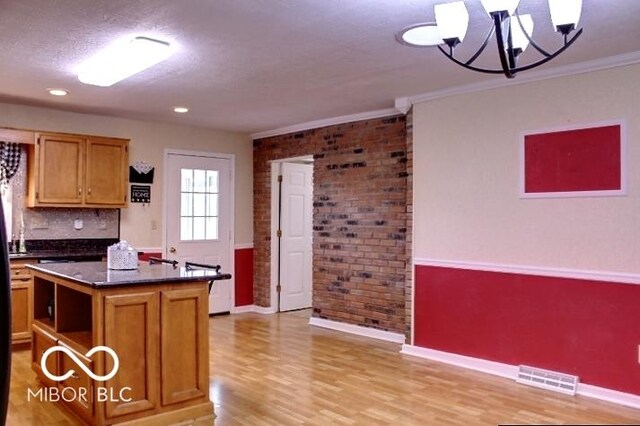 8905 Maze Rd, Indianapolis, IN 46259 - kitchen with dark countertops, light wood finished floors, brick wall, a chandelier, and a kitchen island