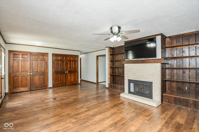 540 Lazy Ln, Greenwood, IN 46142 - unfurnished living room featuring a ceiling fan, ornamental molding, wood finished floors, a textured ceiling, and a brick fireplace