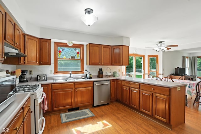 1224 S Hunter Rd, Indianapolis, IN 46239 - kitchen featuring stainless steel dishwasher, white gas range, under cabinet range hood, a peninsula, and light countertops