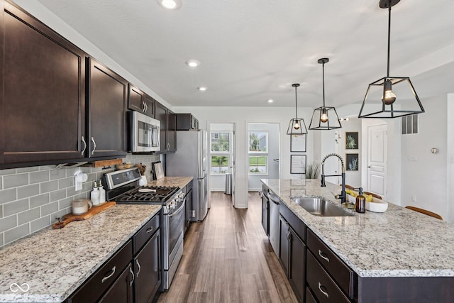 1414 W Springhurst Blvd, Greenfield, IN 46140 - kitchen featuring appliances with stainless steel finishes, dark wood-type flooring, a center island with sink, backsplash, and dark brown cabinetry