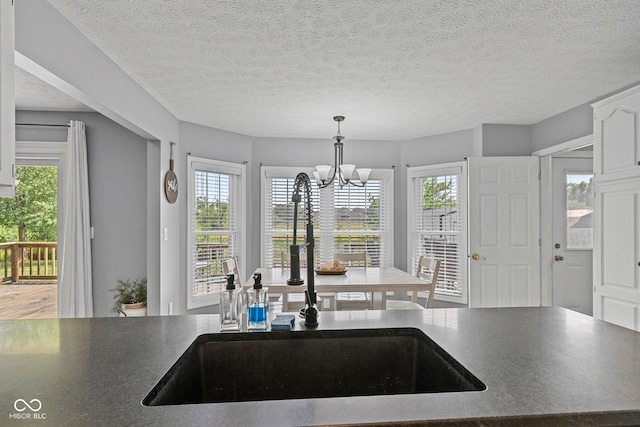 401 N Nicole Ln, Scottsburg, IN 47170 - kitchen with a chandelier, dark countertops, hanging light fixtures, white cabinets, and a textured ceiling