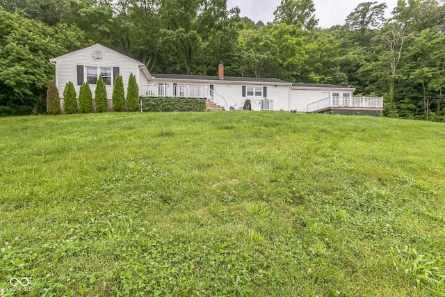8783 State Road 56, Aurora, IN 47001 - view of front of property with a deck, a view of trees, a front yard, and a chimney