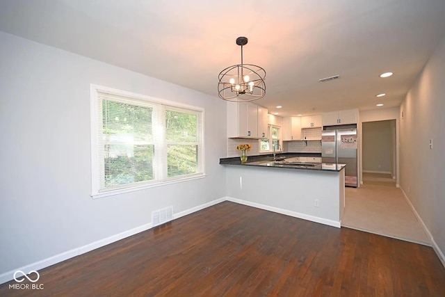 8783 State Road 56, Aurora, IN 47001 - kitchen with freestanding refrigerator, dark countertops, dark wood-style floors, a peninsula, and a chandelier