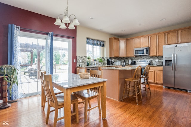 1521 Midnight Pass, Brownsburg, IN 46112 - kitchen with appliances with stainless steel finishes, decorative backsplash, a chandelier, a kitchen island, and wood finished floors