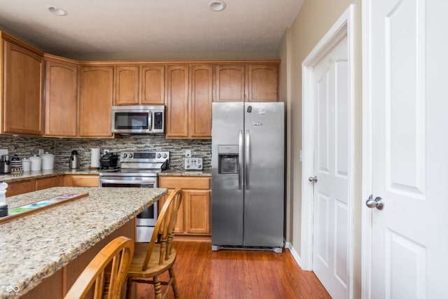1521 Midnight Pass, Brownsburg, IN 46112 - kitchen featuring appliances with stainless steel finishes, dark wood-type flooring, a breakfast bar area, and decorative backsplash