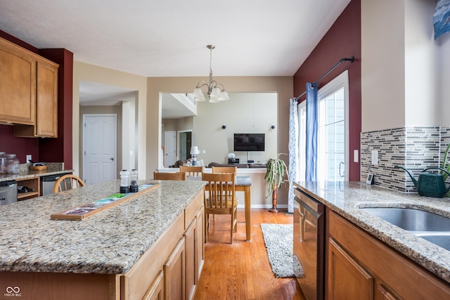 1521 Midnight Pass, Brownsburg, IN 46112 - kitchen with stainless steel dishwasher, light wood-style floors, a chandelier, hanging light fixtures, and decorative backsplash