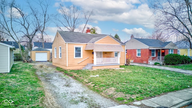 1940 N Drexel Ave, Indianapolis, IN 46218 - bungalow featuring a porch, asphalt driveway, an outbuilding, and a front lawn