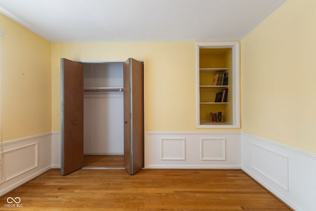 3388 S Leonard Rd, New Palestine, IN 46163 - unfurnished bedroom featuring a wainscoted wall, light wood-style flooring, and a closet