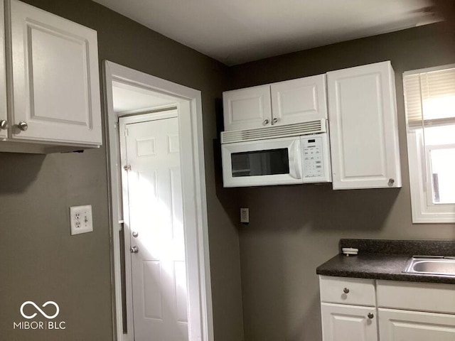 360 Laclede St, Indianapolis, IN 46241 - kitchen with white microwave, dark countertops, and white cabinetry