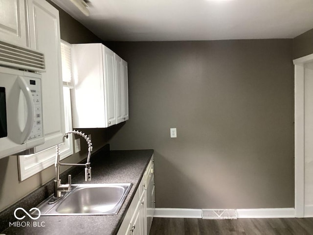 360 Laclede St, Indianapolis, IN 46241 - kitchen featuring white microwave, dark wood-style floors, dark countertops, and white cabinetry