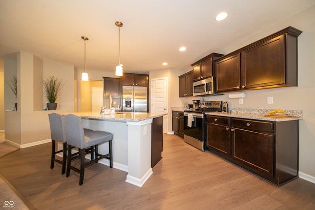 610 Sawtooth St, Westfield, IN 46074 - kitchen featuring appliances with stainless steel finishes, wood finished floors, dark brown cabinets, a kitchen breakfast bar, and recessed lighting