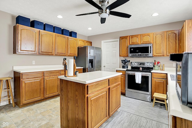5063 Haywood Ln, Plainfield, IN 46168 - kitchen with appliances with stainless steel finishes, a ceiling fan, a kitchen island, light countertops, and recessed lighting