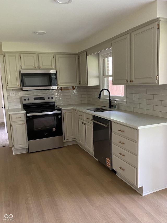 1400 Evelyn Ln, Anderson, IN 46017 - kitchen with stainless steel appliances, light wood-type flooring, light countertops, and tasteful backsplash
