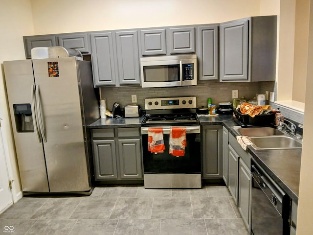 8333 Pine Branch Ln, Indianapolis, IN 46234 - kitchen featuring stainless steel appliances, gray cabinets, dark countertops, and decorative backsplash