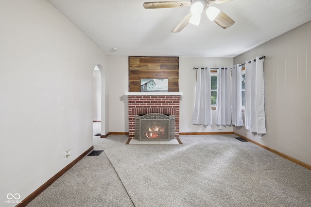 11710 W State Road 32, Yorktown, IN 47396 - unfurnished living room featuring arched walkways, carpet flooring, a ceiling fan, and a fireplace