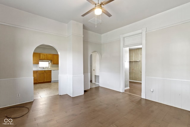 29 E Caven St, Indianapolis, IN 46225 - unfurnished living room with arched walkways, ceiling fan, a wainscoted wall, and wood finished floors