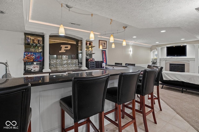 3710 Canada Ct, West Lafayette, IN 47906 - indoor wet bar featuring a textured ceiling, decorative light fixtures, a fireplace, decorative columns, and light tile patterned flooring
